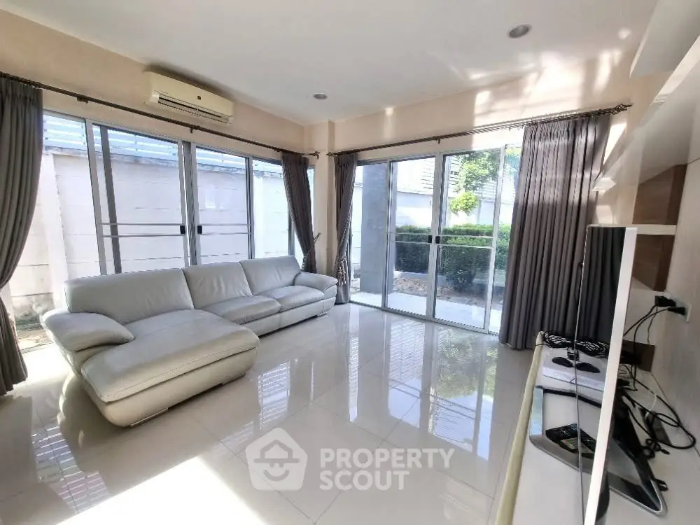 Spacious living room with large windows and modern white sofa, offering abundant natural light.