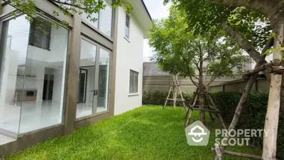 Modern home with lush green garden and large glass windows for natural light.