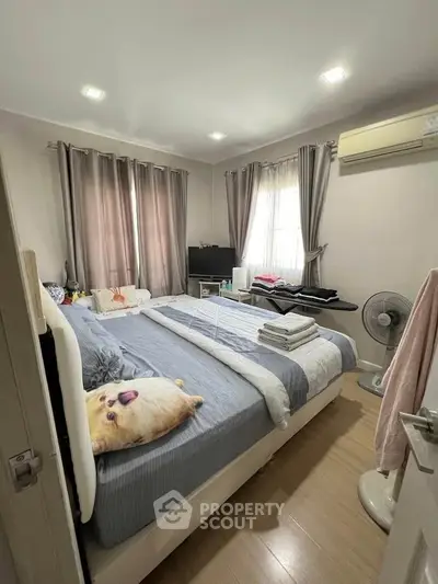 Cozy bedroom with modern decor, featuring a comfortable bed, air conditioning, and ample natural light.