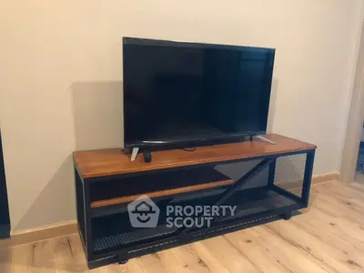 Modern living room with sleek TV stand and flat-screen television on wooden flooring.