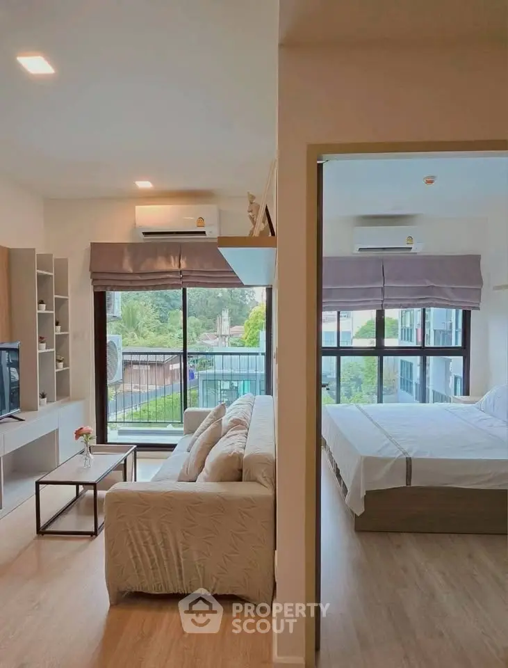 Modern apartment with spacious living room and bedroom, featuring large windows and stylish decor.