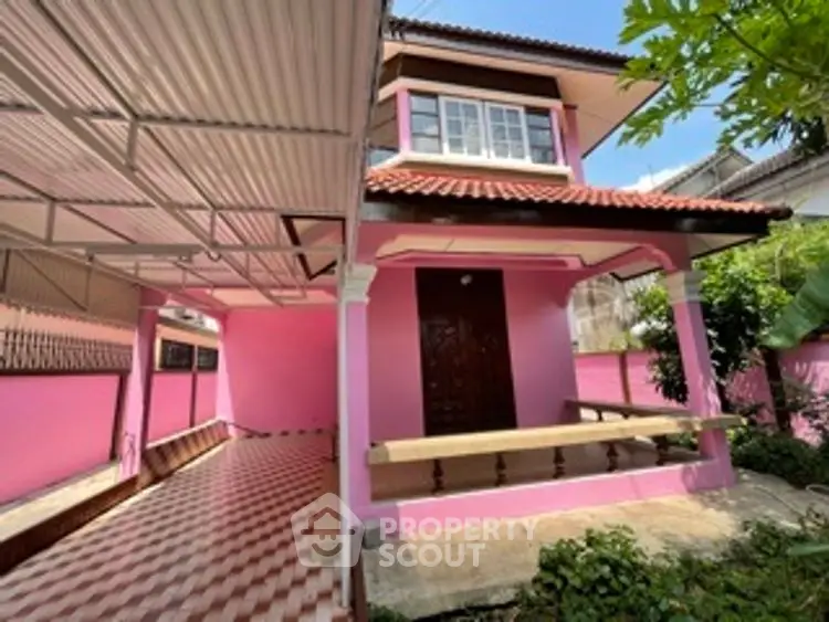 Charming pink house with tiled driveway and lush greenery, perfect for cozy living.