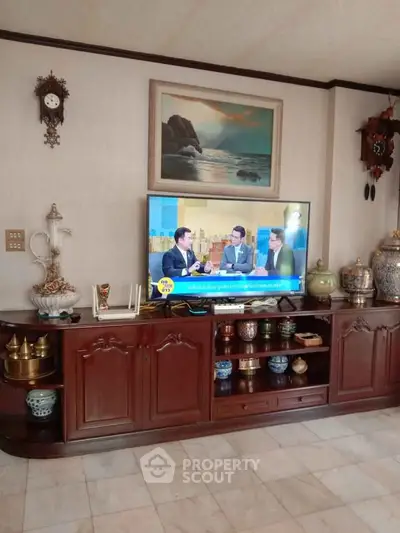 Elegant living room with classic wooden furniture and decorative ceramics, featuring a mounted TV and wall art.