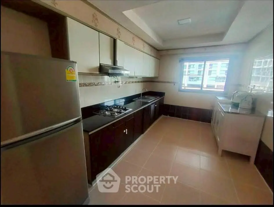 Spacious kitchen with modern appliances and ample natural light in a contemporary apartment.