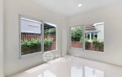 Bright and airy room with large windows and garden view, perfect for relaxation.