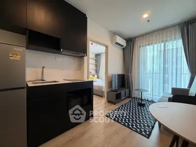 Modern open-layout kitchen and living room with sleek black cabinetry and cozy decor.