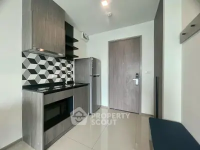 Modern kitchen with sleek cabinetry and stylish backsplash in a compact apartment