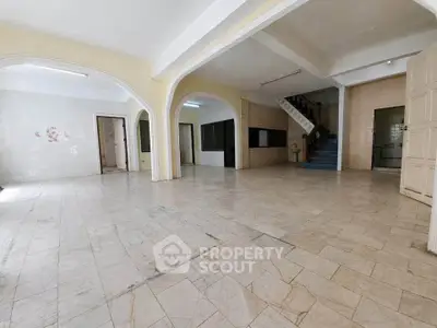 Spacious open-plan interior with tiled flooring and staircase, ideal for renovation.