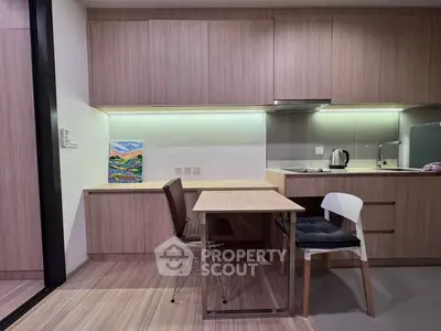 Modern kitchen with sleek wooden cabinets and dining area, featuring contemporary design and efficient use of space.