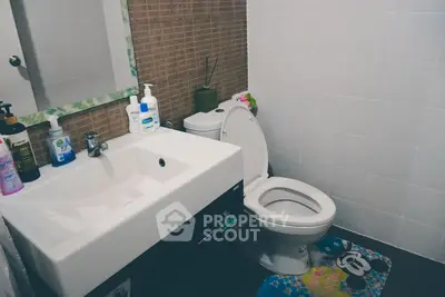 Modern bathroom with sleek sink and toilet, featuring stylish decor and essential toiletries.