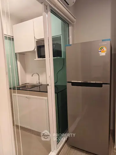Modern compact kitchen with stainless steel fridge and sleek cabinetry