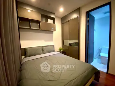 Modern bedroom with cozy bed and sleek storage, adjacent to a bright bathroom.