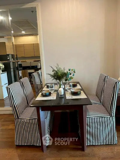 Chic dining area with striped chairs and modern kitchen backdrop, perfect for stylish urban living.