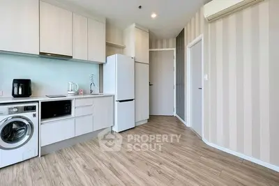 Modern kitchen with sleek appliances and wood flooring in a stylish apartment.