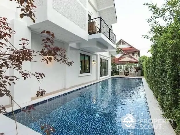 Luxurious private villa with a sparkling blue pool, surrounded by lush greenery and a serene garden, offering a tranquil oasis and outdoor entertainment space.