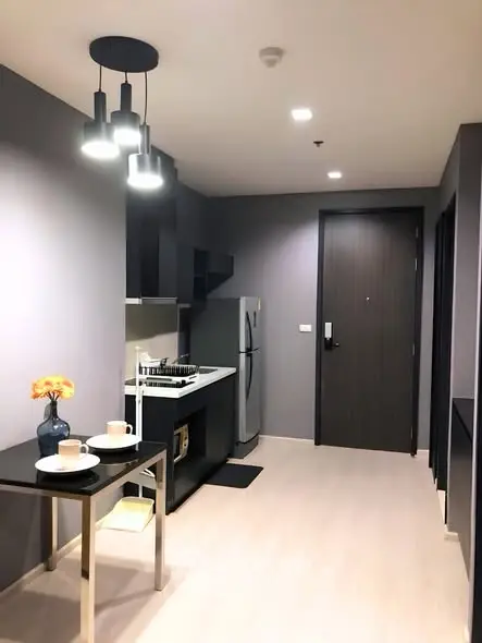 Modern kitchen with sleek design, featuring a fridge, stove, and dining area in a stylish apartment.