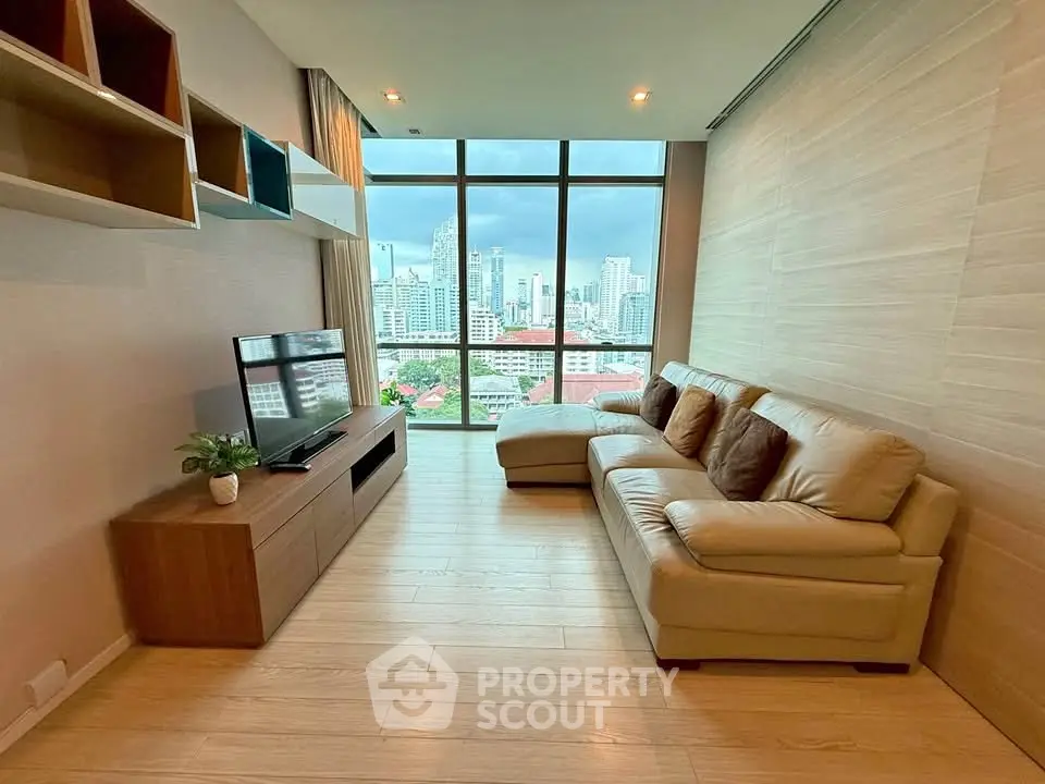 Modern living room with city view, featuring stylish furniture and large windows.