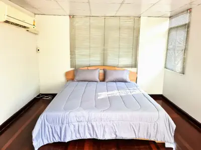 Cozy bedroom with natural light and air conditioning, featuring a comfortable bed and wooden flooring.