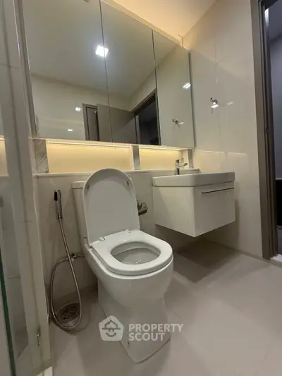 Modern bathroom with sleek fixtures and large mirror in contemporary apartment.