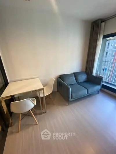 Modern living room with cozy sofa and dining area, featuring large windows for natural light.