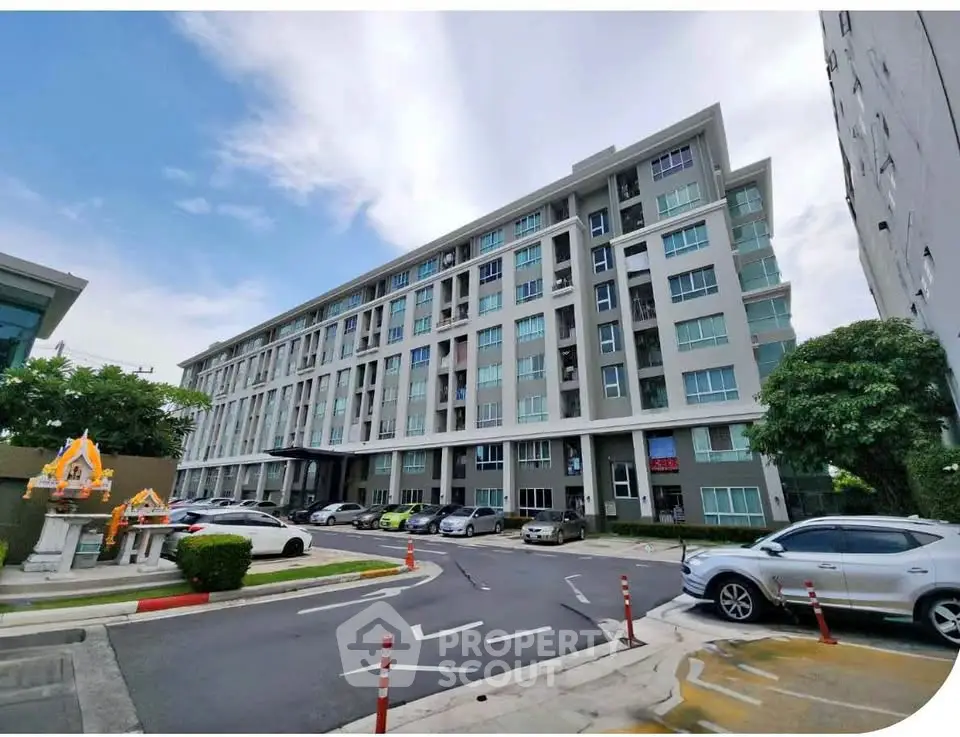 Modern residential building with parking area and lush greenery, showcasing urban living convenience.