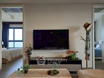 Modern living room with stylish decor and wall-mounted TV, adjacent to a cozy bedroom with natural light.