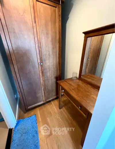 Cozy bedroom corner with wooden wardrobe and dressing table, perfect for compact living spaces.