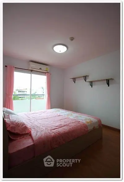 Cozy bedroom with pink decor and natural light from large window.