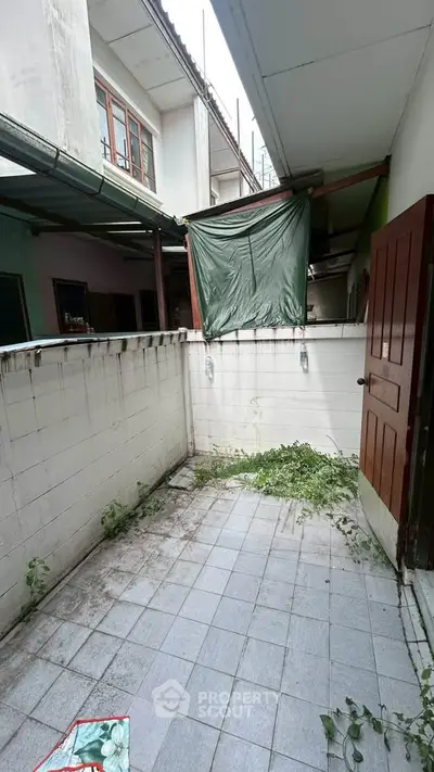 Charming outdoor space with tiled flooring and privacy wall, perfect for a cozy urban retreat.