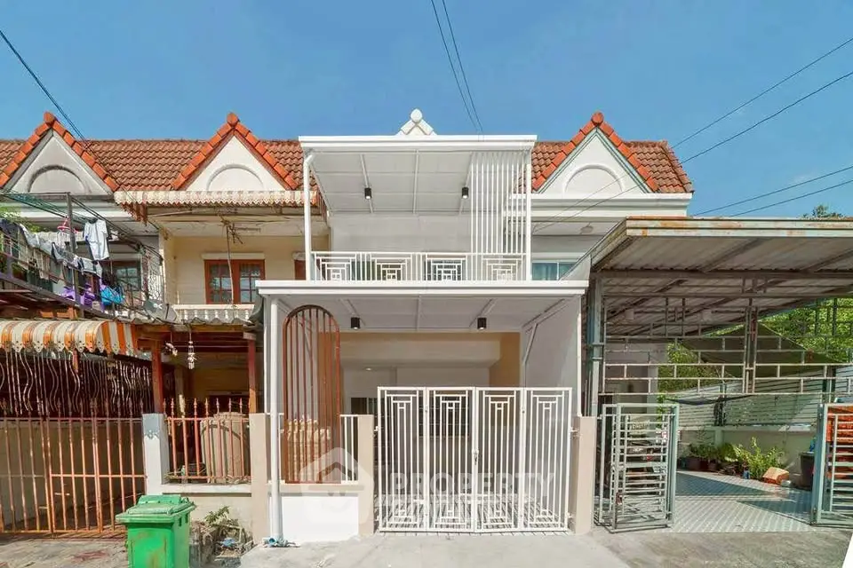 Charming townhouse with red-tiled roof and modern white gate in a serene neighborhood.