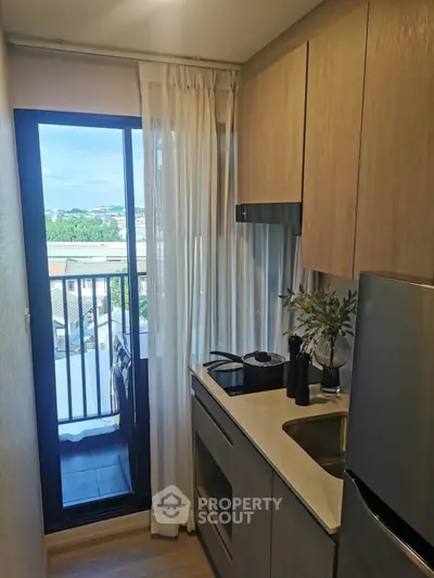Compact kitchen with modern appliances and balcony view