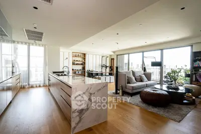 Luxurious open-plan living room with modern kitchen and large windows offering abundant natural light.