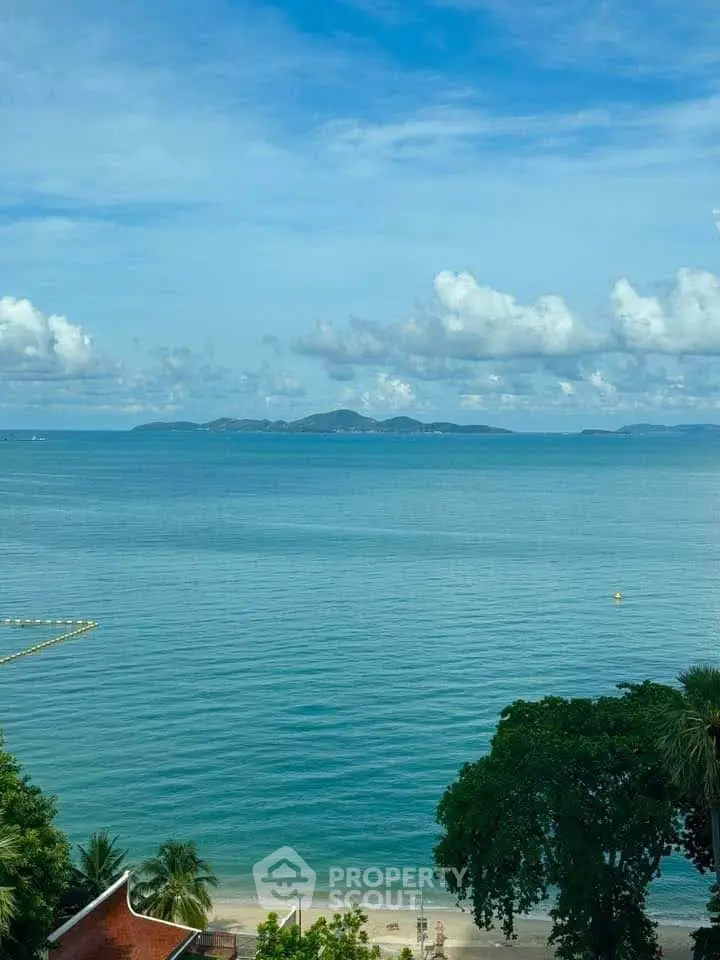 Stunning ocean view from a beachfront property with lush greenery and clear blue skies.