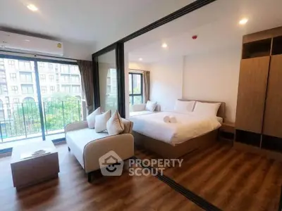 Modern studio apartment with glass partition, cozy seating, and balcony view.