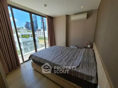 Modern bedroom with large windows offering city views, featuring a comfortable bed and air conditioning.