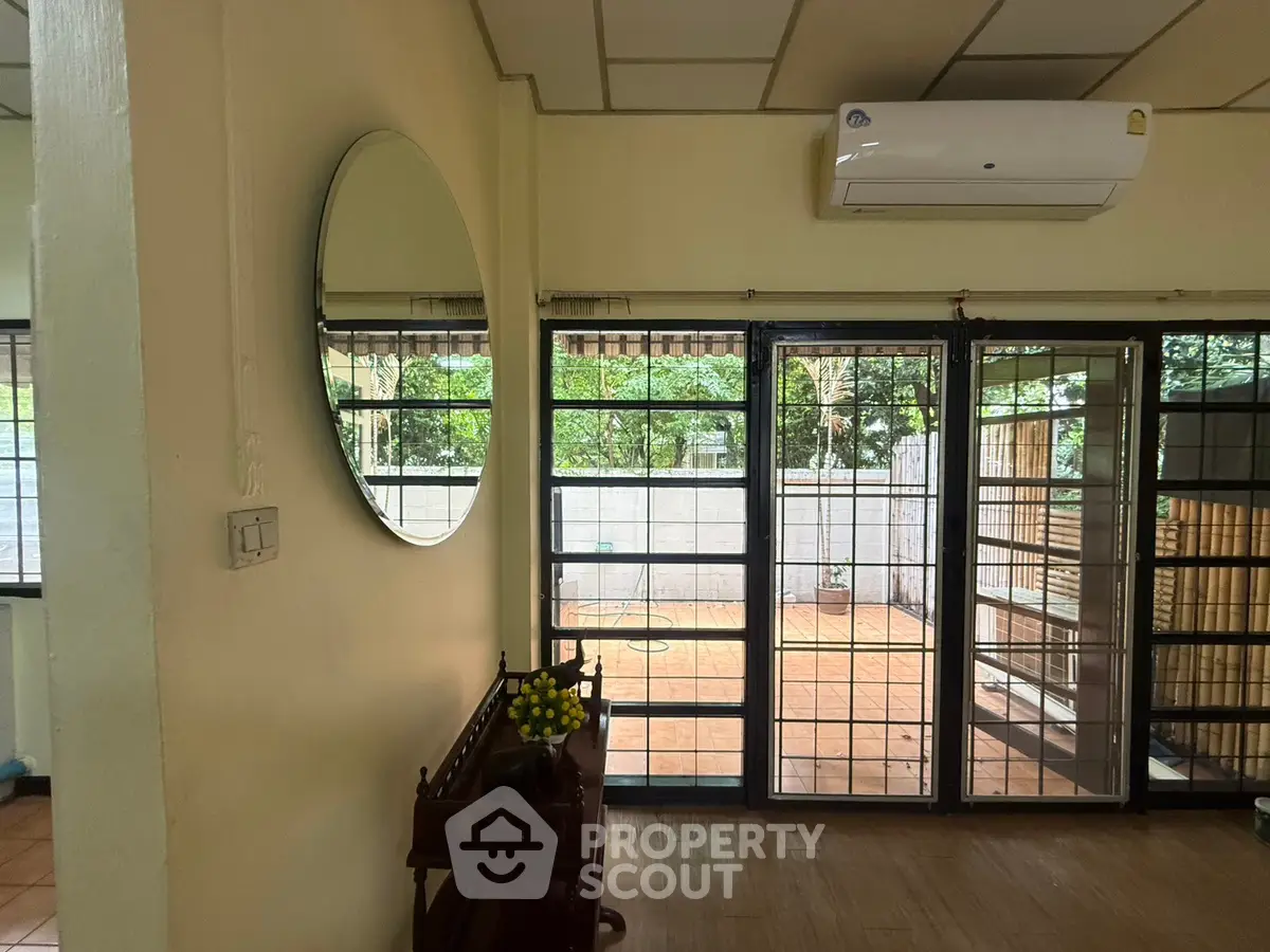 Spacious living room with large windows and garden view, featuring air conditioning and elegant decor.