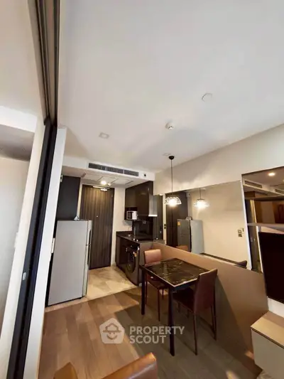 Modern apartment interior with dining area and kitchen featuring sleek appliances and stylish lighting.