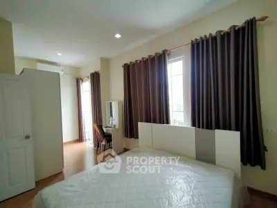 Spacious bedroom with large windows and elegant curtains in modern apartment.