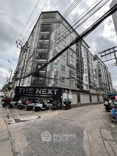 Modern condominium building with street view and motorbikes parked outside.