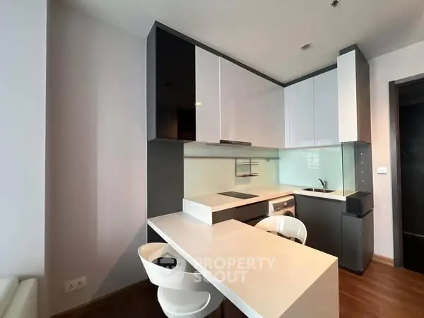 Modern kitchen with sleek cabinetry and breakfast bar in contemporary apartment.