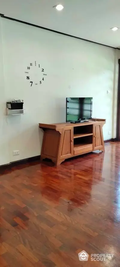 Spacious living room with polished hardwood floors and a unique wall clock design, perfect for cozy family gatherings.