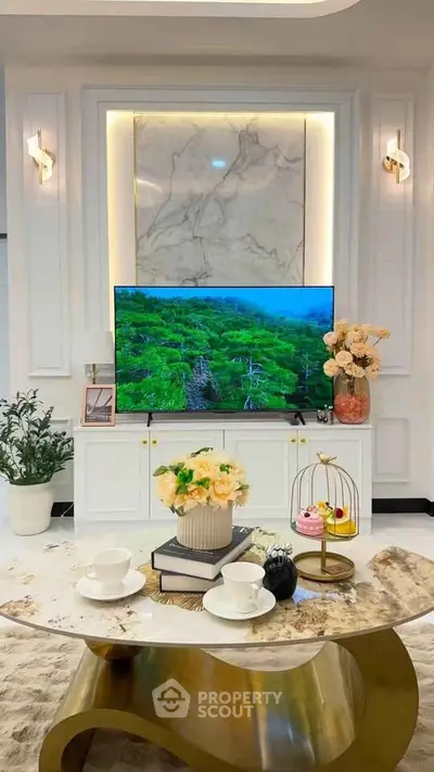 Luxurious living room with elegant decor, featuring a large TV, marble accents, and stylish furniture.