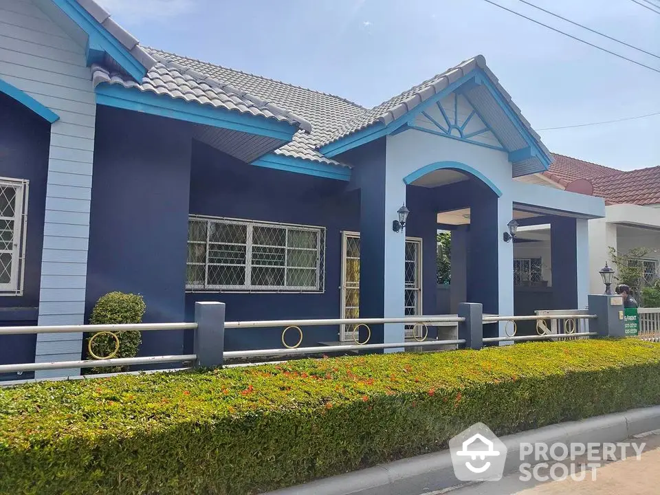 Charming blue house exterior with manicured hedge and tiled roof