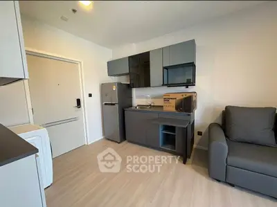 Modern compact kitchen with sleek cabinets and appliances in a cozy apartment setting.