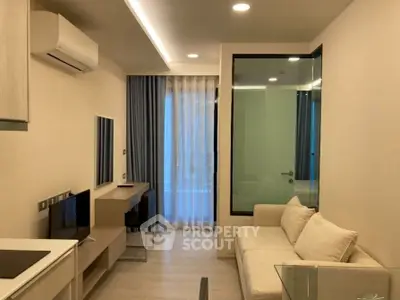 Modern living room with sleek design and glass partition, featuring a cozy sofa and wall-mounted TV.