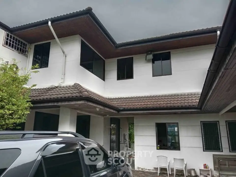 Charming two-story house with tiled roof and spacious driveway, perfect for family living.