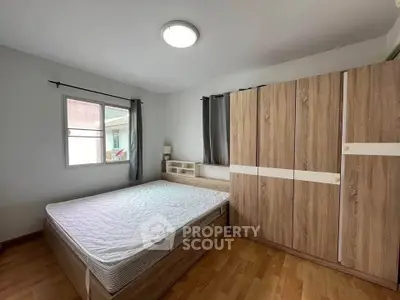 Spacious bedroom with wooden flooring and large wardrobe in modern apartment.