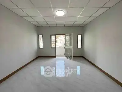 Spacious empty room with glossy floor and balcony access in modern apartment.
