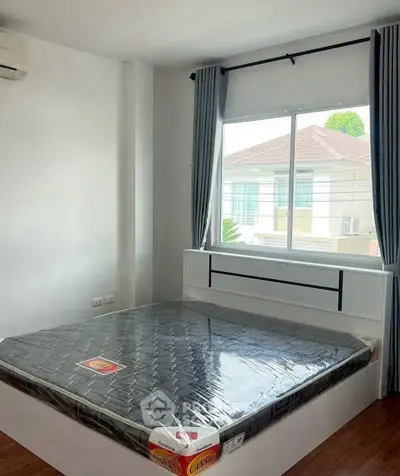 Spacious bedroom with large window and modern bed frame in a bright, airy setting.