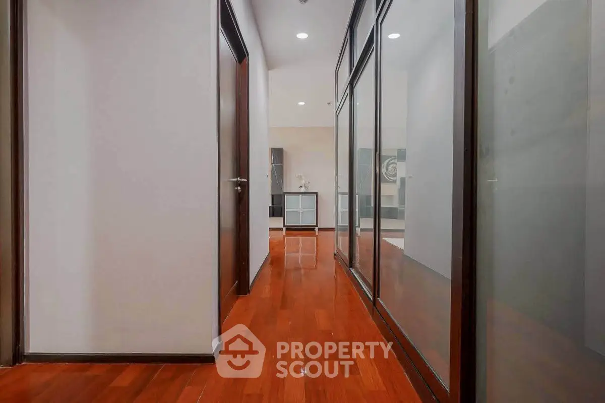 Sleek modern hallway with polished wooden floors and glass partitions in a contemporary office space.